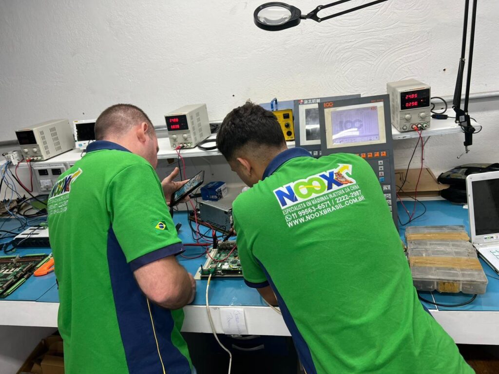 Colaboradores da Noox realizando um conserto em placas de Injetoras da marca Inovance